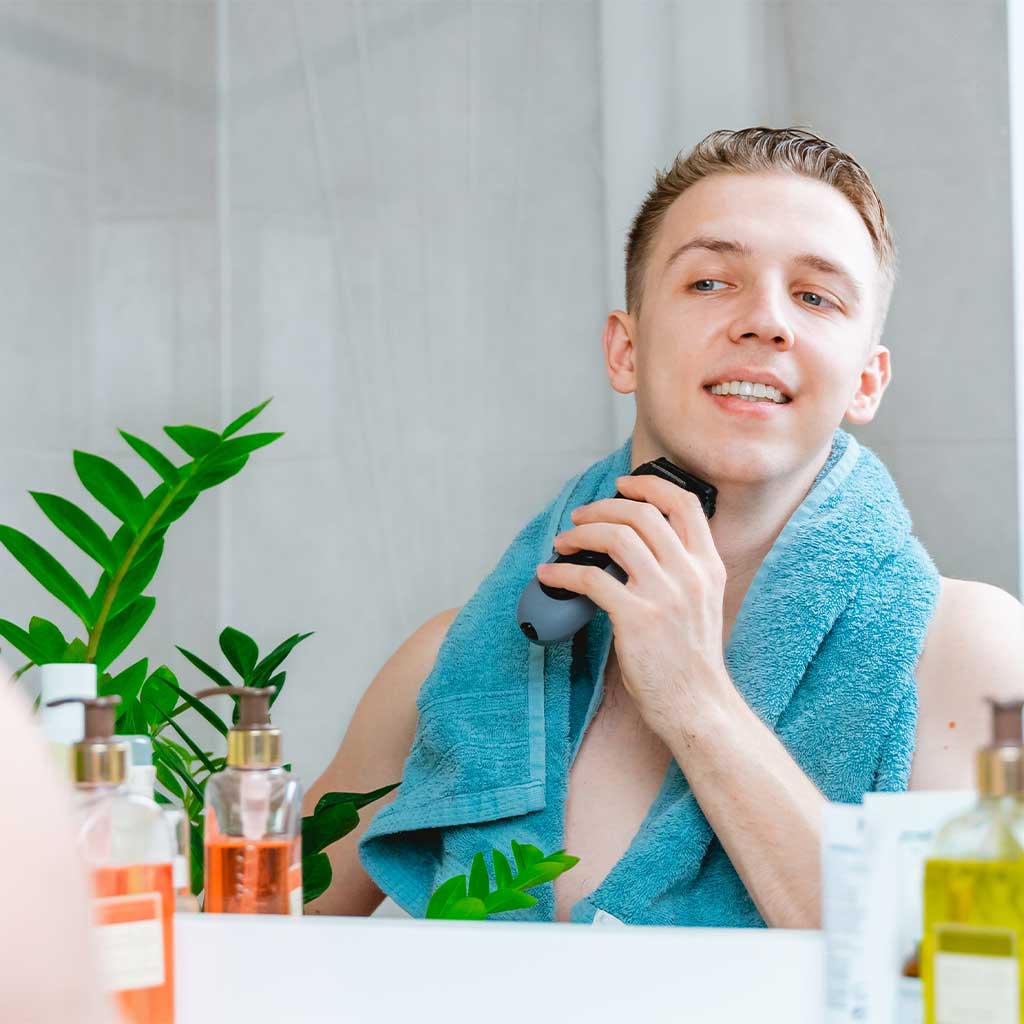Muškarac u kupaonici sa mašinicom za brijanje